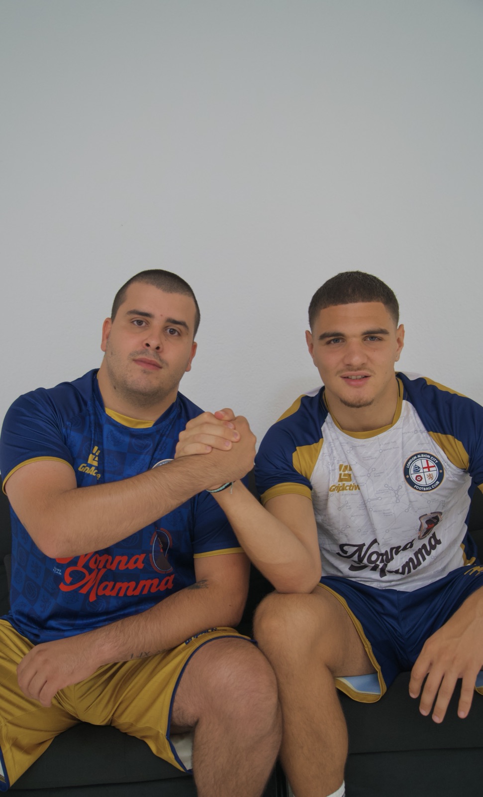 Lorenzo Coppello in blue and Rio Desario in white, clasping hands in club kit